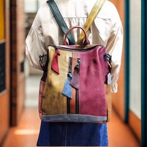 May include: A colourful leather backpack with a patchwork design. The bag features mustard yellow, burgundy, and brown panels, with a vertical zip and decorative tassels. The backpack has adjustable straps and a top handle.