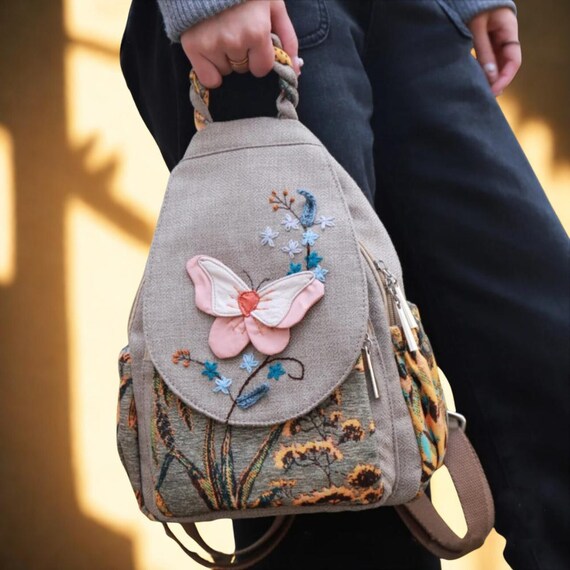 brown leather backpack with embroidered butterflies Beige GG Supreme Canvas Web Butterfly Small Day The model remains consistent 3D Butterfly Embroidered Canvas Backpack: