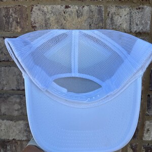 K&ouml;nnte beinhalten: Wei&szlig;e Trucker-Cap mit Mesh-R&uuml;ckseite und gebogenem Schirm. Die Kappe hat einen verstellbaren Druckknopfverschluss. Das Innere zeigt die N&auml;hte und Konstruktionsdetails. Geeignet f&uuml;r den l&auml;ssigen Gebrauch und bietet ein atmungsaktives Design.