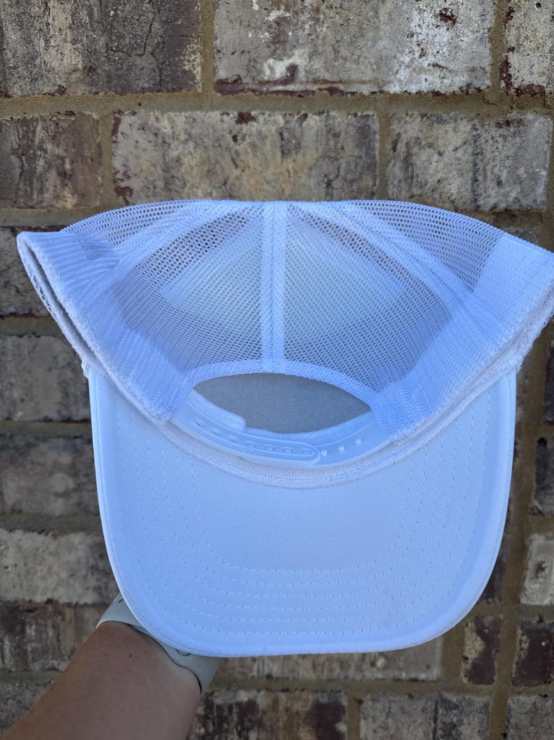 K&ouml;nnte beinhalten: Wei&szlig;e Trucker-Cap mit Mesh-R&uuml;ckseite und gebogenem Schirm. Die Kappe hat einen verstellbaren Druckknopfverschluss. Das Innere zeigt die N&auml;hte und Konstruktionsdetails. Geeignet f&uuml;r den l&auml;ssigen Gebrauch und bietet ein atmungsaktives Design.