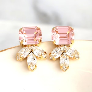 Puede incluir: Un par de pendientes de oro con piedras de cristal rosa y transparentes. Las piedras rosas son de corte esmeralda y las piedras transparentes son de forma marquesa.