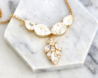 May include: A gold chain necklace with a teardrop-shaped crystal pendant. The pendant is made up of several smaller crystals arranged in a cluster.