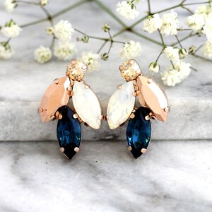 May include: Rose gold earrings with a cluster of blue, white, and peach colored crystals.