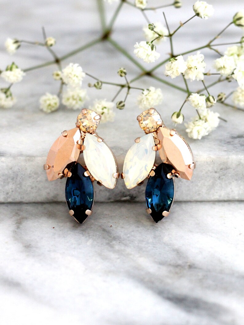 May include: Rose gold earrings with a cluster of blue, white, and peach colored crystals.