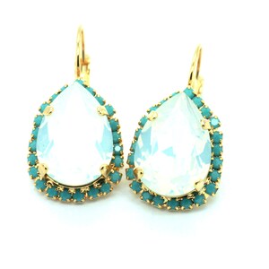 May include: A pair of gold teardrop earrings with a large clear teardrop crystal surrounded by a halo of turquoise crystals.