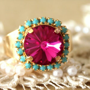 May include: A gold ring with a large, faceted, pink gemstone surrounded by a ring of turquoise stones.