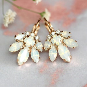 May include: A pair of gold earrings with a cluster of white opal stones. The earrings have a delicate, floral design.
