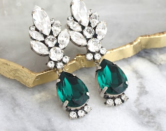 May include: Emerald green teardrop earrings with a cluster of clear rhinestones.