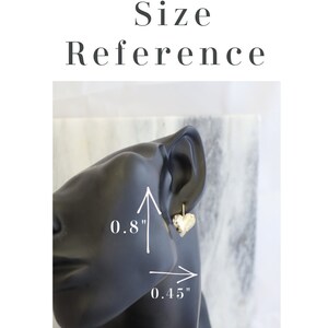 May include: Gold-colored heart-shaped earrings, 0.8 inches in height and 0.45 inches in width, displayed on a black mannequin head. The image includes the text "Earrings Size Reference".