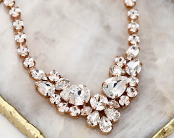 May include: A rose gold necklace featuring a series of clear, faceted crystals in various shapes, including round and pear-cut stones. The necklace is embellished with Swarovski crystals and includes the text Ilona Rubin embellished with Swarovski crystals.