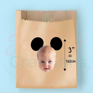 May include: A brown paper bag featuring two black circles and a baby's face. The bag has a 3-inch (7.62 cm) measurement indicator.