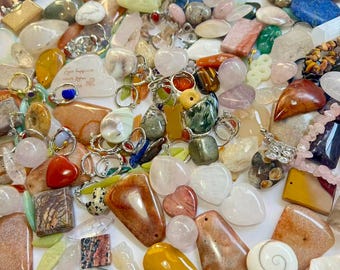 May include: A collection of various gemstone pendants and charms in a variety of shapes, sizes, and colors. The assortment includes heart-shaped, teardrop, and rectangular stones, with silver-toned metal accents. Colors range from pink and white to yellow, brown, and green.