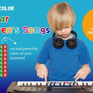 Puede incluir: Un niño con auriculares toca un teclado con notas codificadas por colores. La imagen incluye el texto "Play by Color Popular Children's Songs" y un código QR para una guía de audio gratuita. El teclado tiene notas codificadas por colores para ayudar a los niños a aprender.