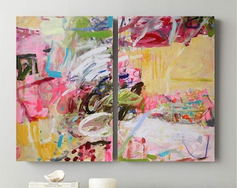 Op de afbeelding: Twee abstracte schilderijen in roze, geel, groen, blauw en wit. De schilderijen zijn op canvas en hebben een textuur. De schilderijen hangen aan een witte muur.