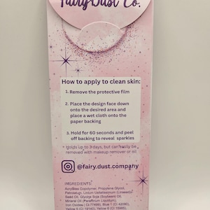 May include: A pink and purple Fairy Dust Co. product package with instructions for use. The package includes the brand name, instructions, and ingredient list. The text reads, "How to apply to clean skin."