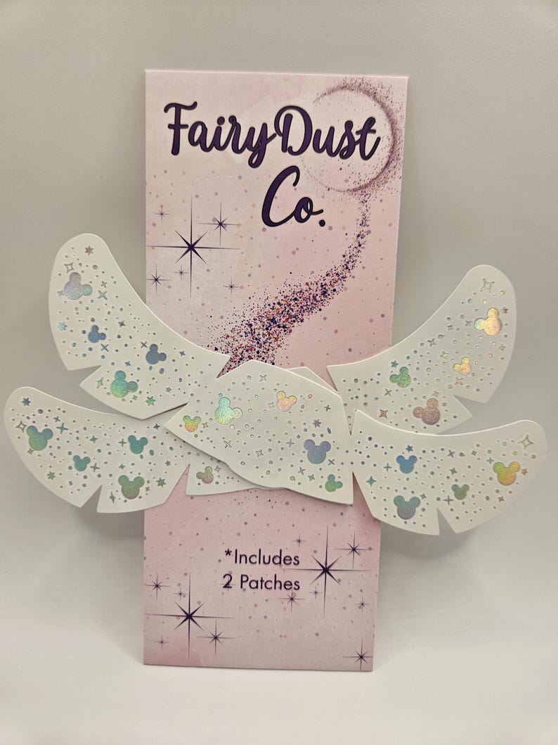 May include: A package of Fairy Dust Co. patches with a pink background and the text "Fairy Dust Co." in purple. The patches are white with iridescent Mickey Mouse head shapes and stars. The package includes 2 patches.