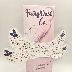 Peut inclure: Un paquet rose de patchs "Fairy Dust Co." avec des étoiles. Les patchs sont blancs avec un motif d'étoiles rouges et de chapeaux de sorcier bleus. Le paquet comprend deux patchs.