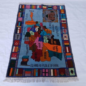 May include: A rectangular rug with a light blue background, depicting a map of the Middle East and surrounding countries. The rug has a border with flags and country names. The map is in various colours, with text labels.