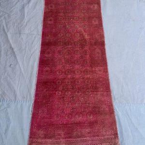 Puede incluir: Una alfombra de corredor rectangular roja con un patrón detallado. La alfombra presenta un diseño circular repetitivo en un tono más oscuro de rojo, con un borde decorativo y flecos blancos en los extremos. La alfombra mide aproximadamente 152 cm de largo.