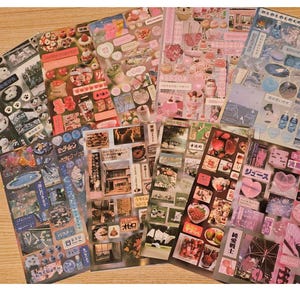 May include: A collection of decorative sticker sheets with various designs. The sheets feature images of food, desserts, and Japanese text. The color palette includes pink, white, and blue, with a wooden surface in the background.