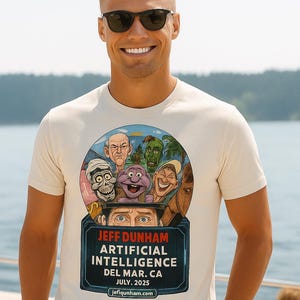 May include: Off-white t-shirt featuring a colorful graphic of ventriloquist dummies and the text "JEFF DUNHAM ARTIFICIAL INTELLIGENCE DEL MAR. CA JULY. 2025". The shirt is worn by a person wearing sunglasses.