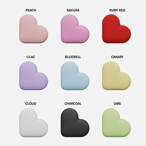 May include: Nine heart-shaped objects in various colors, including peach, sakura, ruby red, lilac, bluebell, canary, cloud, charcoal, and lime. Each heart has a smooth, rounded design and is labeled with its corresponding color name.