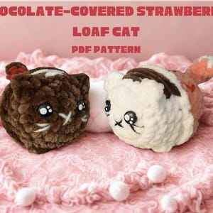 May include: Two crocheted cat-shaped plushies, one brown and one white, resembling chocolate-covered strawberries. The text "CHOCOLATE-COVERED STRAWBERRY LOAF CAT PDF PATTERN" is displayed above. The plushies are on a pink, textured surface.
