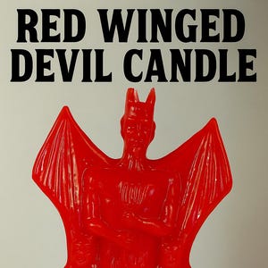 Puede incluir: Una vela roja con forma de diablo con grandes alas, cuernos y un cuerpo detallado. El texto "RED WINGED DEVIL CANDLE" en negrita negra está en la parte superior. La vela es de color rojo vibrante.