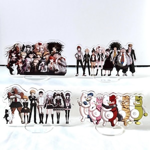 Op de afbeelding: Vier acryl display stands met anime-personages. De stands tonen verschillende groepen personages in verschillende poses en outfits. Het kleurenpalet omvat zwart, wit, rood en andere levendige kleuren. Elke stand heeft een heldere basis.
