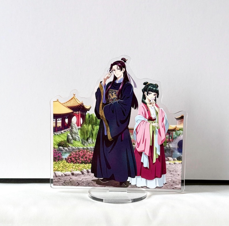 Puede incluir: Soporte acr&iacute;lico con dos personajes de estilo anime con vestimenta tradicional china. El personaje masculino viste una t&uacute;nica azul oscuro con detalles dorados, mientras que el personaje femenino lleva un atuendo rosa y rojo. El fondo representa un jard&iacute;n chino.