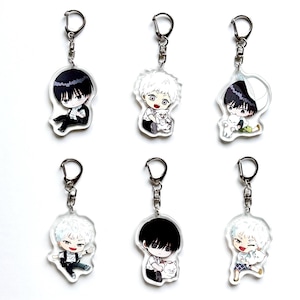 May include: Six anime-style keyrings with cartoon characters, some holding a white cat. Each keyring has a silver metal ring and a clear acrylic charm. The characters have black and white hair and are in different poses.