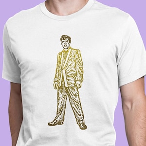 May include: A white t-shirt with a gold-colored illustration of a man in a suit. The man is standing with his legs spread apart and his arms at his sides. The illustration is in a vintage style.