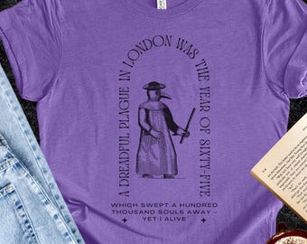 May include: A purple t-shirt with a graphic of a plague doctor and text that reads "A dreadful plague in London was the year of sixty-five." The shirt is paired with blue jeans and an open book.