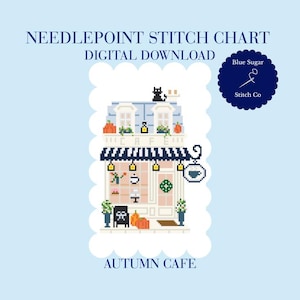 May include: A needlepoint stitch chart digital download titled Autumn Cafe. The design features a pixelated cafe building with a blue roof, a black cat, orange pumpkins, and a hanging sign with a coffee cup icon. Text includes Blue Sugar Stitch Co.