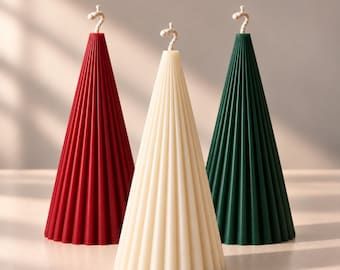 May include: Three cone-shaped candles with a vertical ribbed texture. One candle is deep red, one is off-white, and one is dark green. Each candle features a single braided cotton wick at the top center, standing upright on a flat surface.