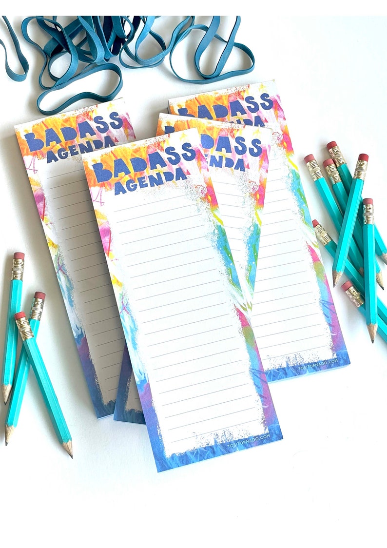 Pile of Badass Agenda notepads surrounded by rubber bands and cute mini teal pencils