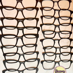 Puede incluir: Gafas recortadas en blanco y negro con nombres escritos en blanco en cada par. Los nombres son Quinn, Reese, Harper, Otis, Jessie, Drew, Murphy, Casper, Larkin, Wanda, Ella, Otero, Kirby, Cedro, Serra, Twain, Finley y Soto. Las gafas est&aacute;n dispuestas en dos columnas, con la parte superior de cada columna comenzando con el nombre Quinn y Reese. La parte inferior de cada columna termina con el nombre Ella y Soto. El texto "Glammering Glasses" est&aacute; escrito en rosa y blanco con un gr&aacute;fico de unicornio debajo.
