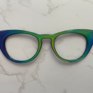 May include: A pair of cat-eye glasses with a gradient blue to green frame.