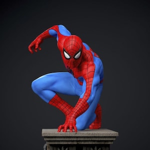 May include: A red and blue Spider-Man figurine in a crouching pose. The figure is on a stone pedestal against a dark background. The costume features a web pattern on the red areas and white eye lenses.