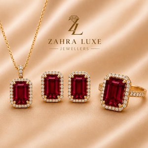 Puede incluir: Un conjunto de joyas de oro que incluye un collar, dos pendientes rectangulares y un anillo, cada uno con una piedra preciosa roja de corte esmeralda rodeada por un halo de pequeños diamantes blancos. Se ve el nombre ZAHRA LUXE JEWELLERS.