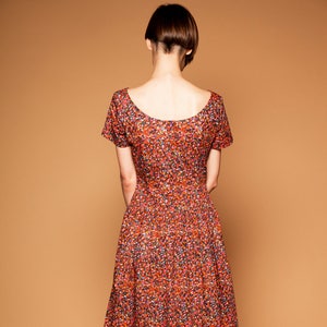 May include: A red, orange, and blue floral print midi dress with short sleeves and a scoop neckline.