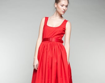 Puede incluir: Una mujer con un vestido rojo sin mangas, un cinturón rojo y tacones grises.
