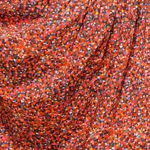 May include: Close-up of a red fabric with a small, colorful confetti pattern.