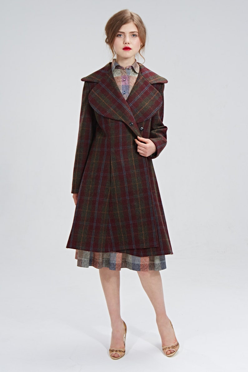 May include: A long, burgundy and green plaid coat with a large, folded collar. The coat has a button closure and a slightly flared skirt.