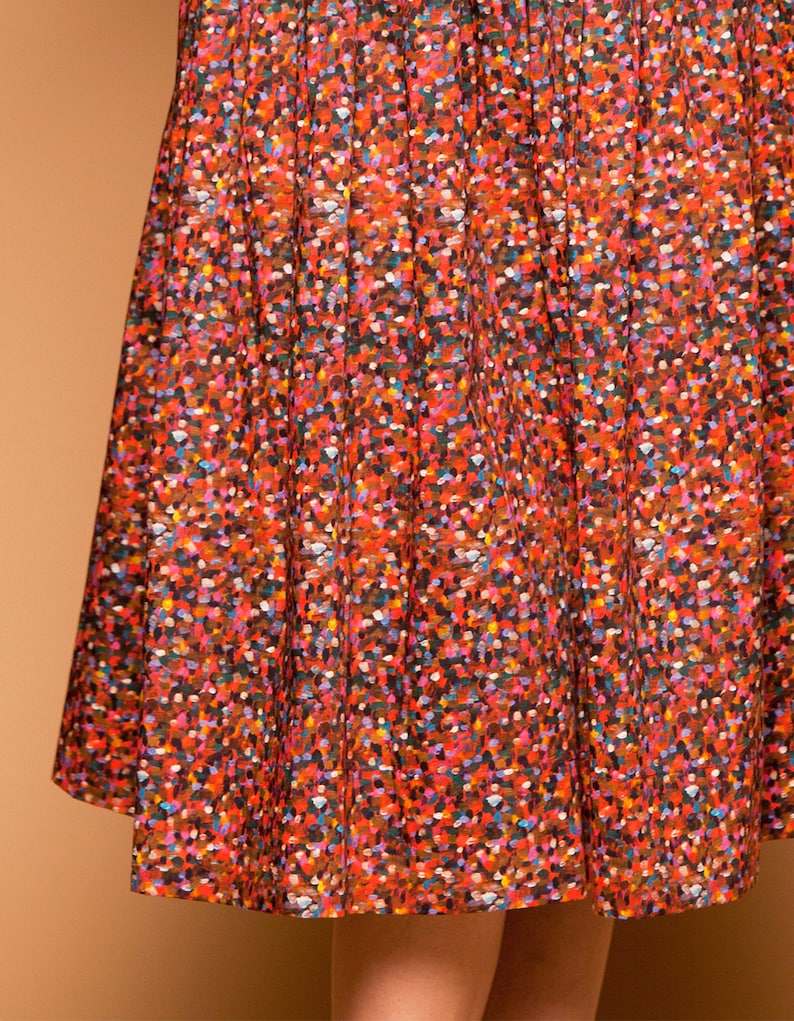 May include: A red skirt with a colorful confetti print. The skirt is made of a lightweight fabric and has a flowy silhouette.