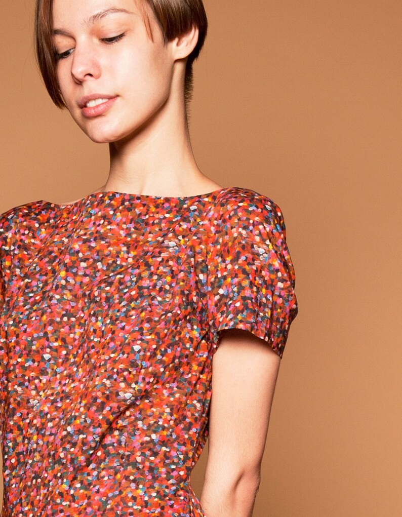 May include: A woman wearing a short-sleeved red dress with a colorful confetti print.