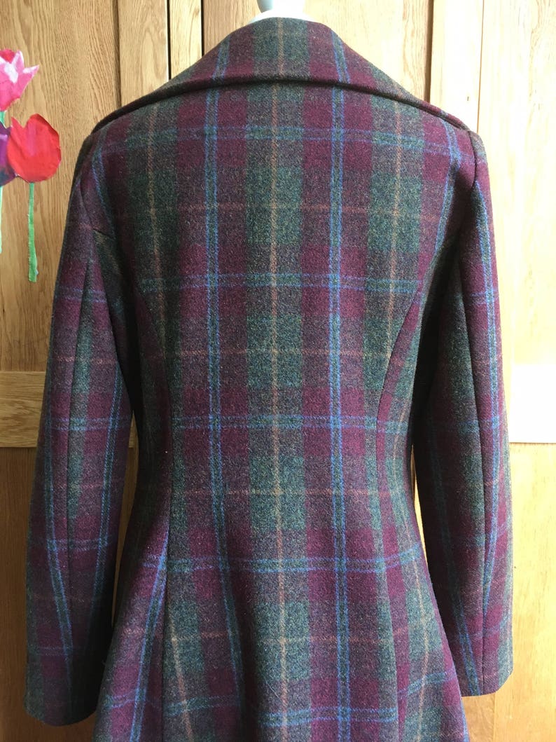 May include: A burgundy, green, and blue plaid coat with a collar and long sleeves.