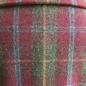 May include: Close-up of a burgundy, green, and blue plaid fabric. The fabric has a fuzzy texture and is woven in a plaid pattern.