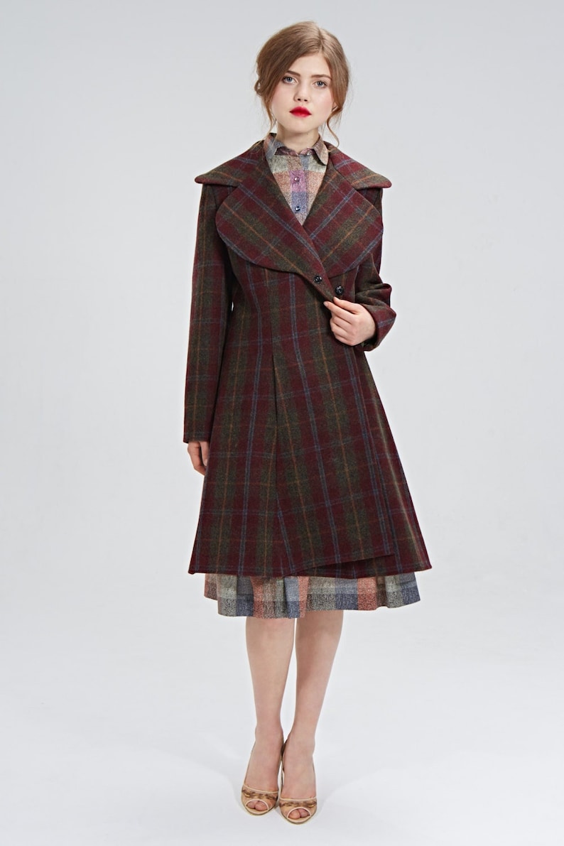May include: A red and green plaid coat with a large collar and a skirt underneath. The coat has a button closure and a long, flowing silhouette.