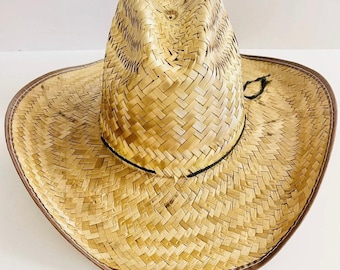 May include: A woven straw cowboy hat with a brown leather trim and a black hat band. The hat has a classic western design with a wide brim and a tall crown. The hat is made of natural straw material.